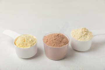 Protein powder. A spoonful of protein powder on a table. Different flavors of whey protein powder. Sports nutrition concept. Gym. Amino acid food supplement, creatine powder. Copy space.
