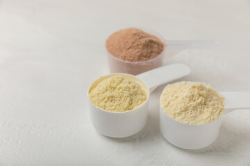 Protein powder. A spoonful of protein powder on a table. Different flavors of whey protein powder. Sports nutrition concept. Gym. Amino acid food supplement, creatine powder. Copy space.