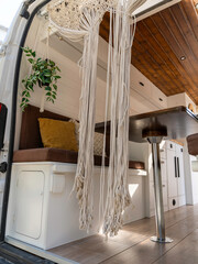 Interior of a Nordic-style camper van with macramé curtains