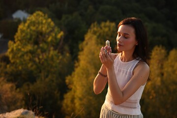 Woman meditating with crystal to heal or restore her aura outdoors, space for text