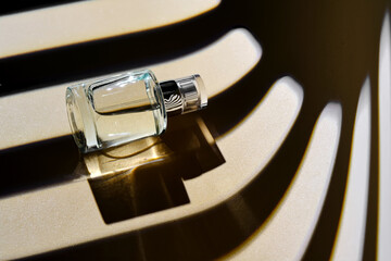 Is the perfume spray bottle lying on a beige background with shadow stripes.