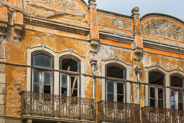 Weathered facade of old building with ornate balconies