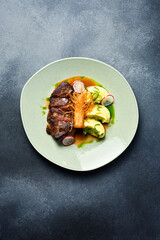 Veal steak with enoki mushrooms and potatoes. In a plate. Restaurant dish. Close up.