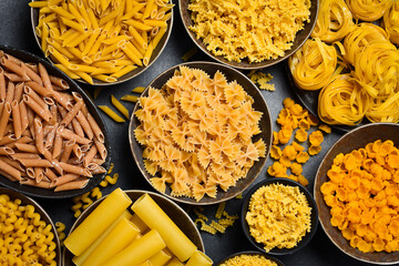 Pasta. Various kinds of uncooked pasta and noodles in bowls. Gluten free products. Set of pasta on kitchen background.