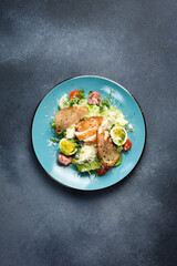 Fresh vegetable salad with chicken fillet and egg. Traditional Caesar salad. In a blue plate.