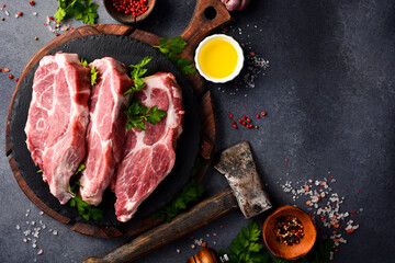 Three Raw pork steak with spices on a plate. Raw meat. On a gray stone background.