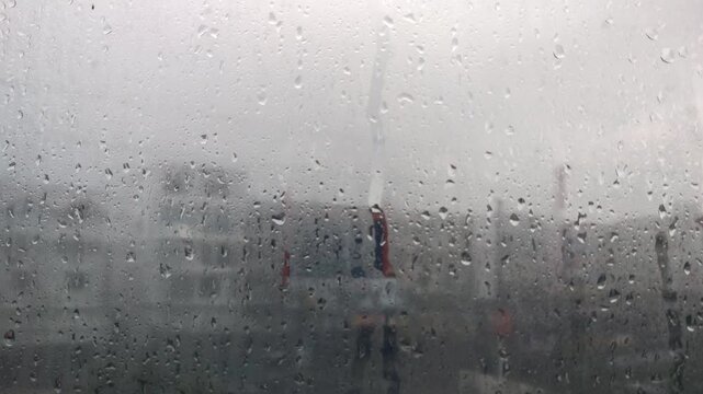 Raindrops on a foggy window obscure the view.