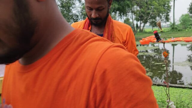 Footage of Kanwariya devotees taking a ritual bath in a village pond before collecting holy water (Gangajal) during sacred Kanwar Yatra pilgrimage in India. Ritual bathing is important purification