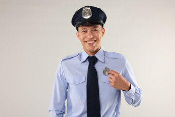 Young policeman in uniform on light grey background
