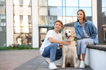 Couple with their adorable golden retriever dog in on city street. Space for text