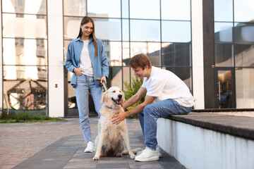 Couple with their adorable golden retriever dog in on city street