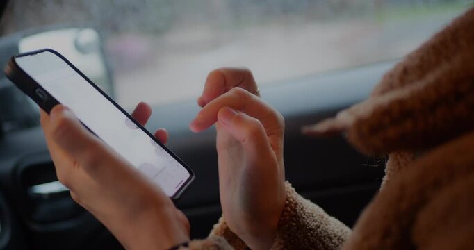 Close-up of hands scrolling right to left on a smartphone screen inside a car, focusing on touchscreen interaction, technology, mobile browsing, digital communication, and modern lifestyle on the move
