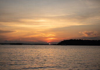 Serene Sunset Over Water with Silhouetted Horizon