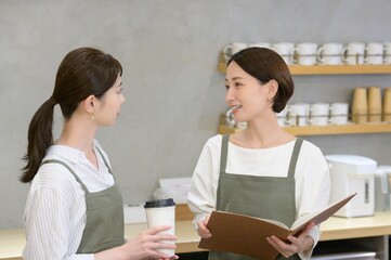 カフェの受付でメニューを見て話し合う日本人女性