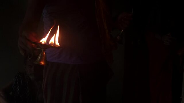 Traditional Hindu Aarti ceremony featuring a glowing oil lamp (Aarti Diya) with multiple flames. The sacred ritual is performed as an offering to the deity during temple worship in India