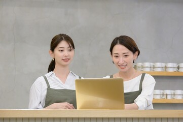 カフェの受付でパソコンを見て悩む日本人女性