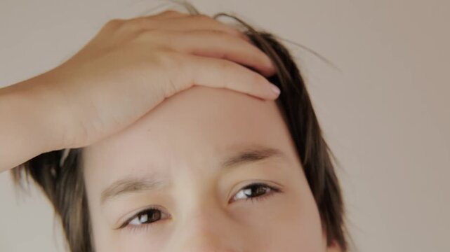 Sick teenage boy 13 years old suffering from fever and headache at home, child holding head showing signs of flu or illness, Youth health crisis concept
