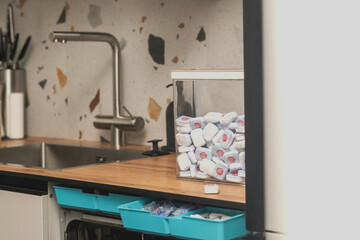 Kitchen with a dishwasher and a container filled with dishwasher tablets.