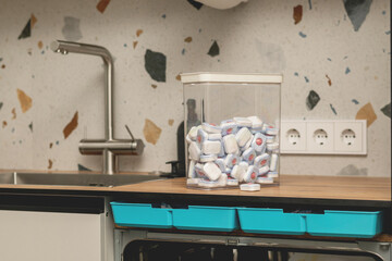Kitchen with a dishwasher and a container filled with dishwasher tablets.