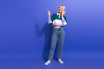 Smiling young woman on call gestures in casual outfit with purple background