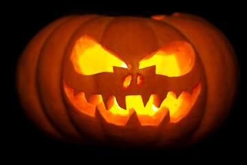Halloween pumpkin with a scary glowing face on a black background.