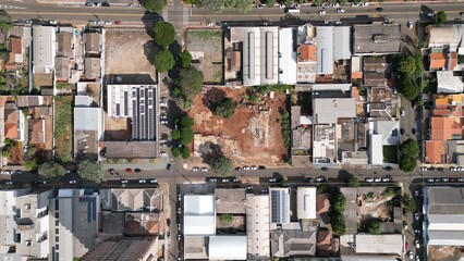 Aerial photo taken by drone showing an empty lot in the middle of an urban area surrounded by residential and commercial buildings. The image highlights city planning, street layout, and architectural