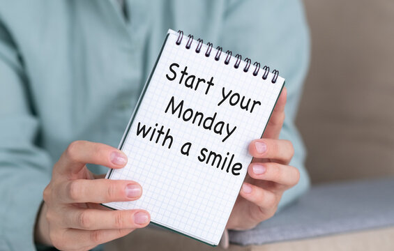 A person holding a notebook with the words Start your Monday With a Smile written on it