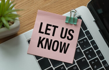 A pink note with the words Let us Know written on it is sitting on top of a la