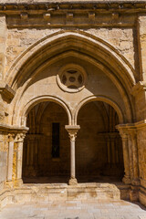 A sunlit stone archway with a central column and circular window frames
