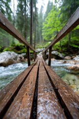 Wooden bridge over rushing river in a lush forest during a rainy day