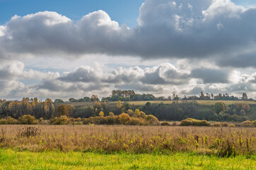 Golden autumn on a hilly plain covered with meadows and forest.