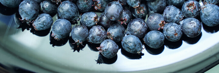 Fresh blueberries on reflective surface displaying natural texture and color.