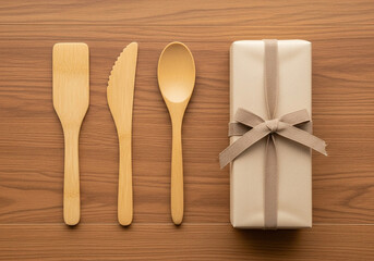 Ecofriendly bamboo cutlery set and a gift box wrapped with burlap ribbon on wooden table