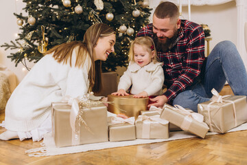 Happy family opening christmas gifts near decorated tree
