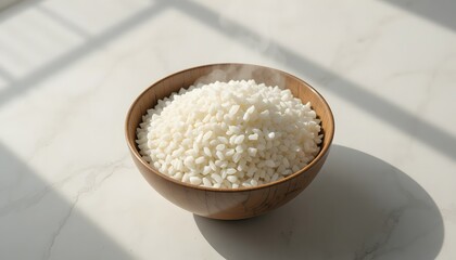 Bowl of steaming rice on light surface.