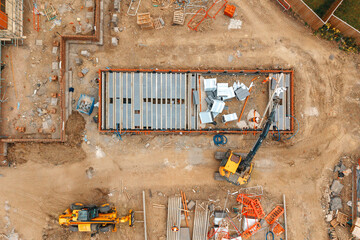 Construction site showing heavy equipment and building materials during daytime in a developing area