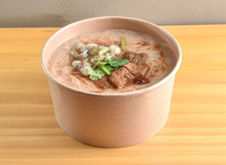 Taiwanese Oyster Vermicelli Noodle Soup Mee Sua with Braised Pork Intestine and Cilantro in bowl on wooden table side view of Asian cousin