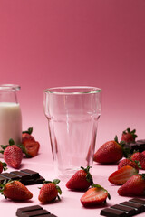 Pink background with empty glass and strawberries
