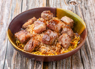 Succulent Sizzling Beef Cubes and Rice Topped with Savory Glaze in a Rustic Bowl on wooden table side view of asian cousin