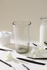 Glass cup with flowers and vanilla on gray backdrop