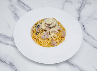 Spaghetti with Chicken, Mushrooms, and Parmesan in a Rich Black Truffle Cheese Sauce on White plate isolated on marble background top view