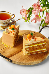 Two slices of orange cake with tea and flowers creating a cozy atmosphere