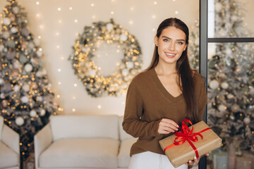 Smiling Woman Holding Gift in Festive Christmas Setting