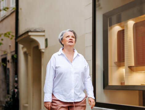Mature caucasian woman walking in urban setting near store display