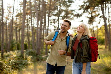 Couple enjoys a joyful hike through the forest in golden evening light