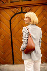 Stylish young woman smiles while posing near a wooden patterned wall