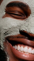 Obraz premium Joyful African American man with stubble smiles broadly, showcasing a facial mask, highlighting self-care and wellness in a close-up portrait with vibrant textures