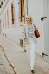 Stylish woman walking casually down a charming street in a quaint neighborhood during the daytime