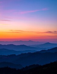 Obraz premium A serene landscape captures a vibrant sunset over silhouetted mountain ranges, with a gradient sky showcasing orange and purple hues