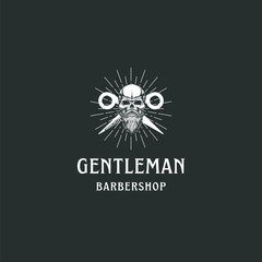 Vintage gentleman barbershop logo with skull, scissors, and beard for edgy branding and stylish design projects promoting barber culture